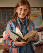 Smiling girl in Bluebell Rose Garden bomber jacket reads a book, showcasing stylish kids clothes for school adventures.