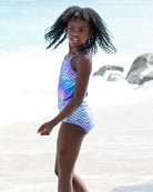 Iridescent Mermaid Taylor Swimsuit on a girl at the beach, showcasing vibrant colors and playful design.