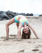 Joyful girl in a colorful Rainbow Polka Dots Swimsuit doing a backbend on the beach, showcasing playful summer fun!