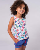 Joyful girl in a butterfly print tank top, ready for fun in kids' clothes—stylish and comfy for summer playdates!
