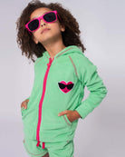 Stylish child in a mint hoodie with heart design, rocking pink sunglasses—a fun addition to kids' clothes!
