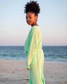 Confident girl in a mint green beach sweater, ready for sunny adventures and playful days at the shore!