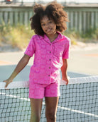 A stylish girl in a pink resort shirt and shorts, ready for sun-soaked adventures in high-quality kids clothes.