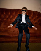 Cool kid in luxurious Midnight Velvet Plaid Suit Pants, stylishly lounging on a plush couch with sunglasses.