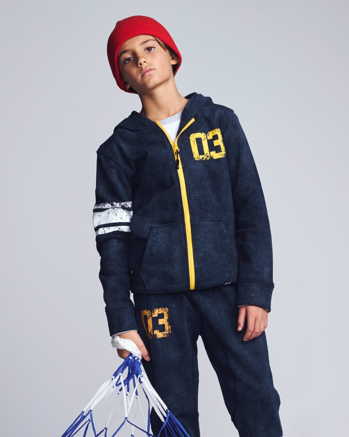 Child wearing a navy hoodie with yellow accents and matching pants on a plain background