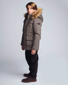 Person wearing a checkered coat with fur hood on a light gray background