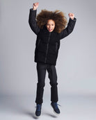 Child wearing a black jacket and pants on a gray background