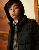 A boy wearing a black hooded puffer jacket. Appaman Fall/Winter 2026 collection.