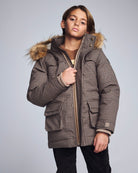 Person wearing a checkered winter coat with fur hood on a gray background