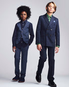 Two children wearing formal suits on a plain background