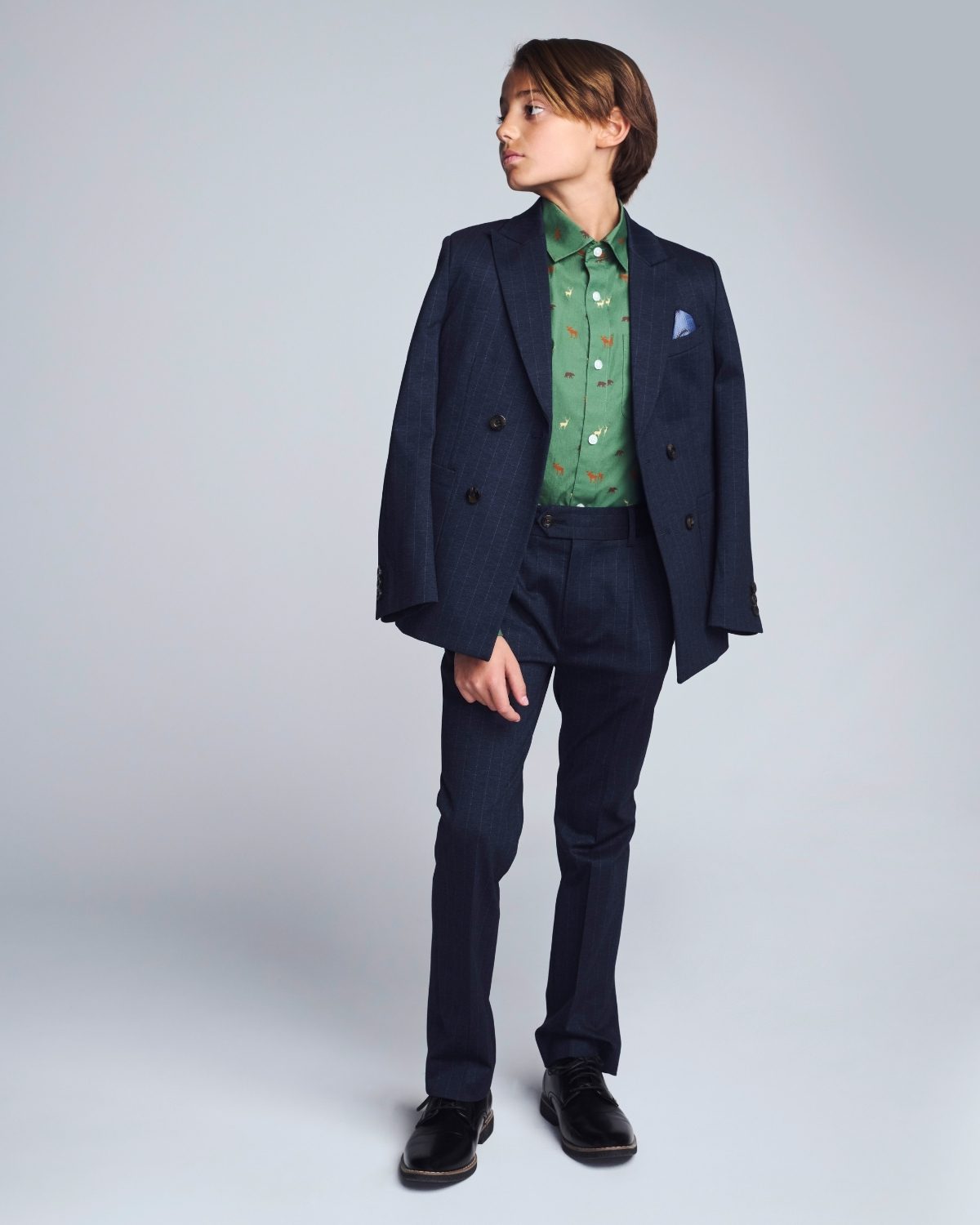 Person wearing a navy suit with a green patterned shirt on a light gray background