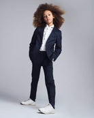 Child wearing a navy suit with a white shirt on a gray background