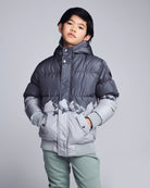 Child wearing a gray puffer jacket with mountain design on a light gray background