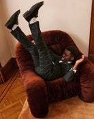A boy in a tuxedo, playfully posed on a velvet chair. Appaman Fall/Winter 2026 collection.
