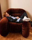 A boy in a tuxedo, playfully posed on a velvet chair. Appaman Fall/Winter 2026 collection.