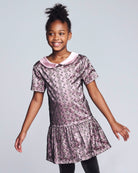 Young girl wearing a floral dress with a pink collar against a light gray background