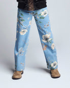Light blue jeans with floral pattern worn by a person on a white background