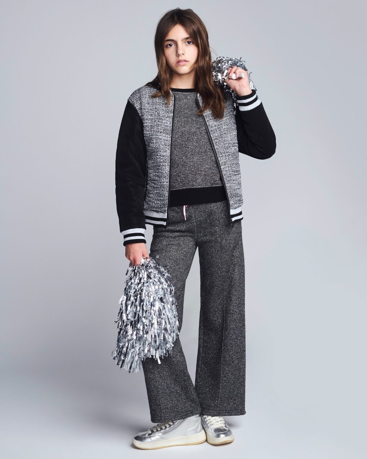 Person wearing a gray and black outfit with pom-poms on a white background