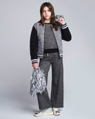 Person wearing a gray and black outfit with pom-poms on a white background