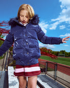 Child wearing a blue puffer jacket with a hood in an outdoor setting