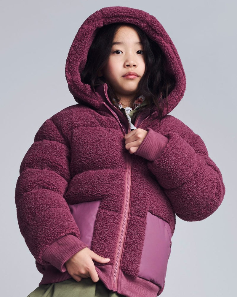Child wearing a purple fleece jacket on a gray background