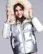 Person wearing a silver puffer jacket with a fur-lined hood on a gray background
