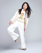 Young girl in a white outfit with a teddy bear design on a gray background
