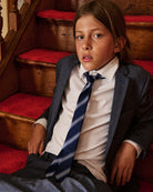 A child in a navy blazer and striped tie posed on a staircase. Appaman Fall/Winter 2026 collection.