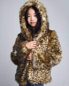 Girl wearing a leopard print fur coat against a plain background