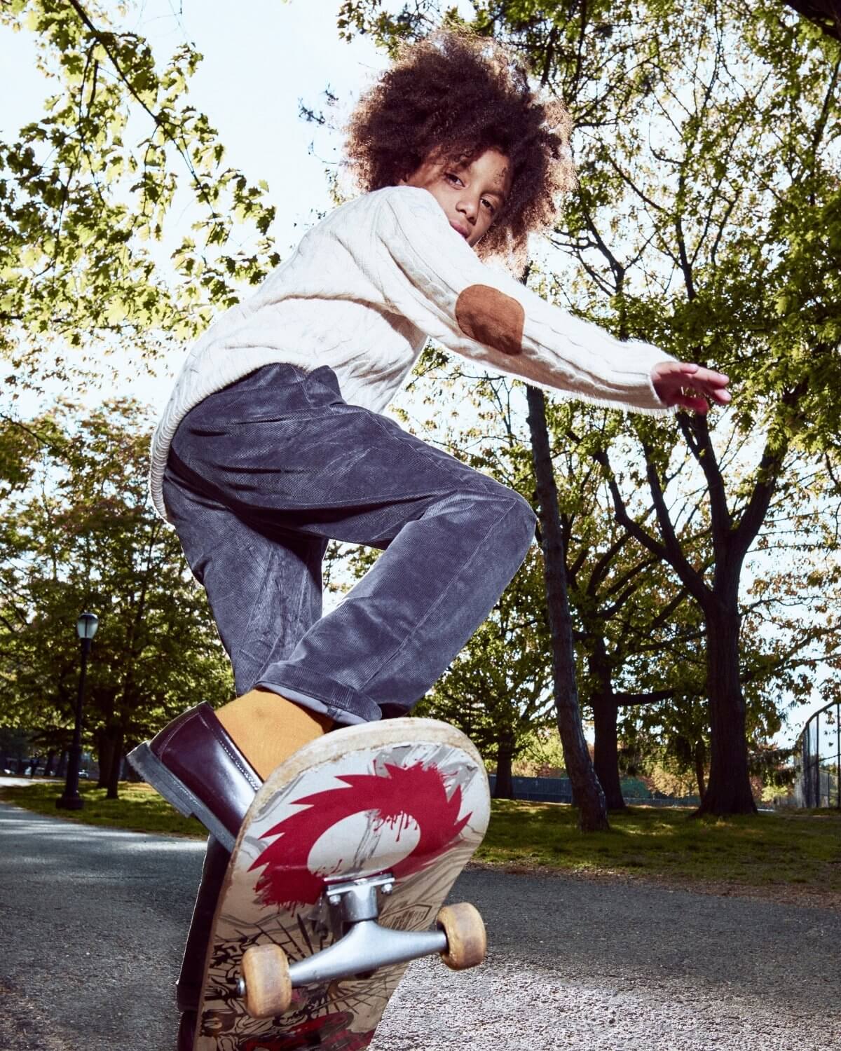 Person skateboarding in a park with trees and clear sky