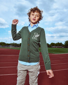 Child wearing a green cardigan with a logo on a track field