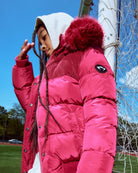 Person wearing a pink puffer jacket with a hood in an outdoor setting