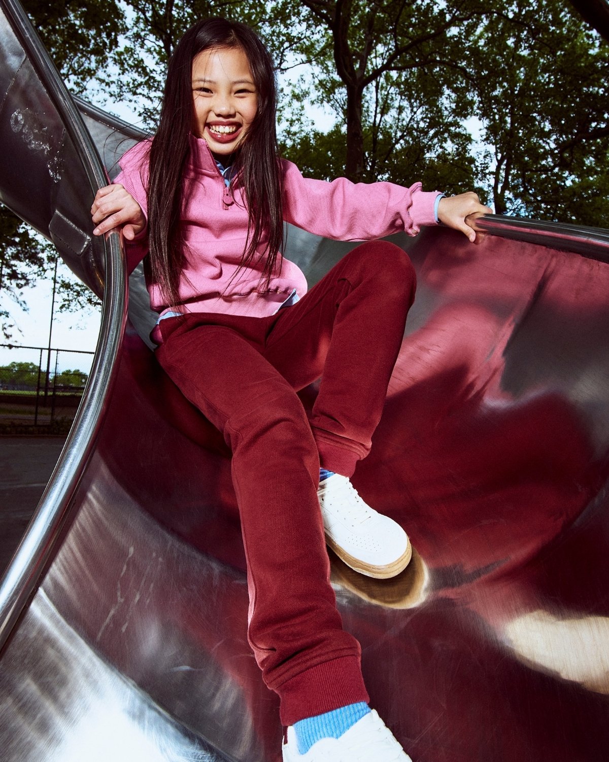 Child sliding down a playground slide with trees in the background