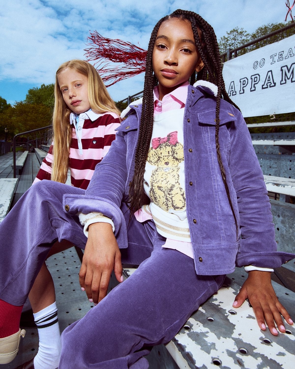 Two young girls sitting on a bench with a colorful background