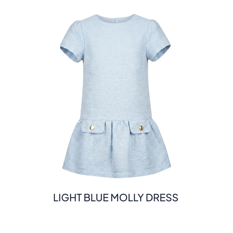 A light blue short-sleeve dress for toddlers, featuring a textured fabric, a peplum waist, and two front pockets with gold-tone buttons. The text 'LIGHT BLUE MOLLY DRESS' is displayed below the product on a solid white background.