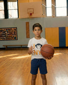 Child holding a basketball in a gymnasium