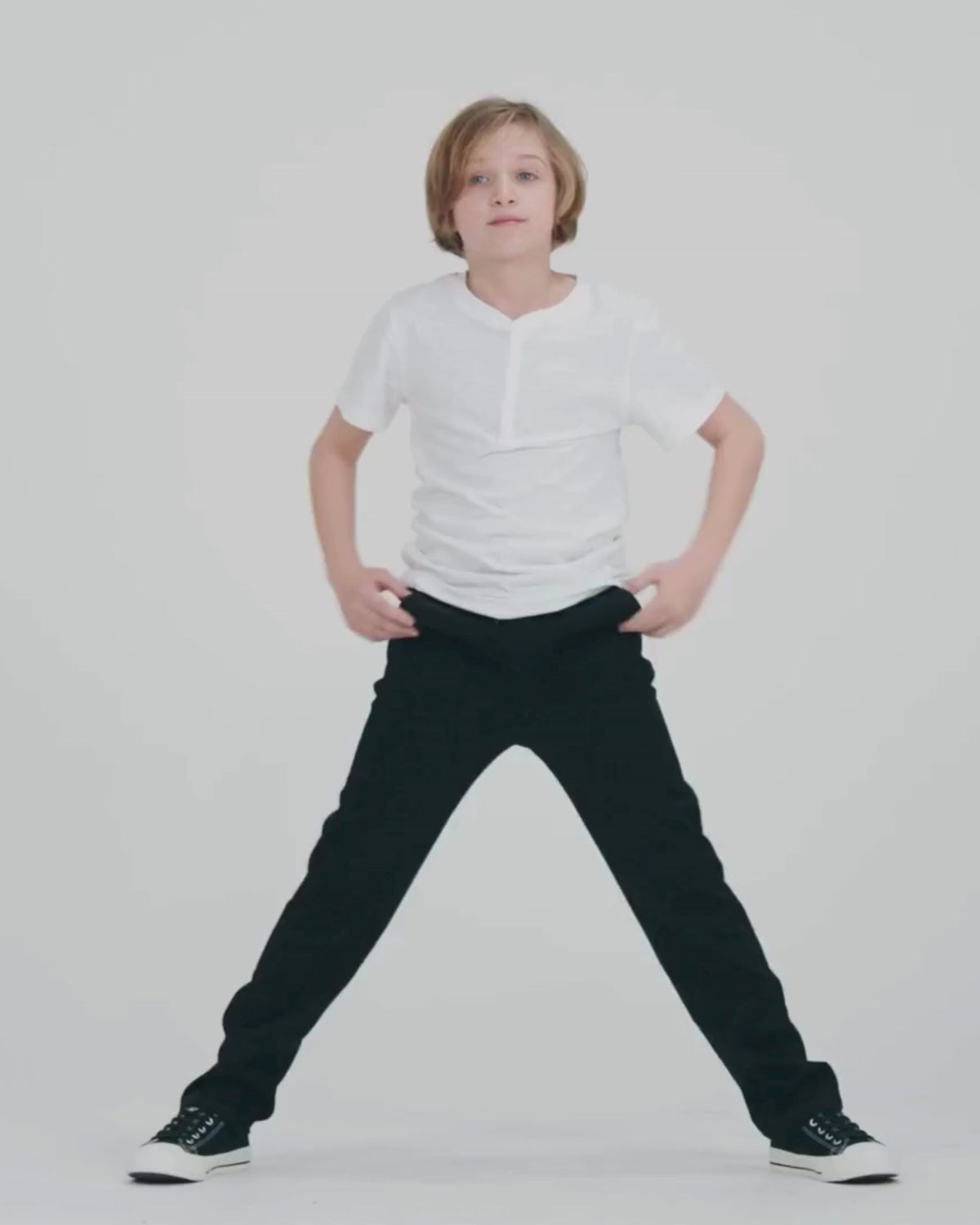 Child wearing Black Everyday Stretch Pants, running playfully in a dynamic pose on white background.