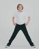 Child wearing Black Everyday Stretch Pants, running playfully in a dynamic pose on white background.